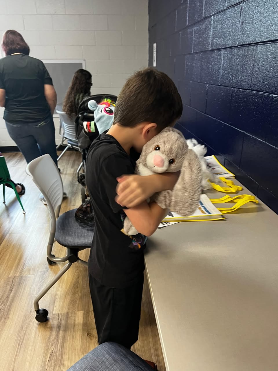 A child proudly holding a finished Furry Friend at a library workshop
