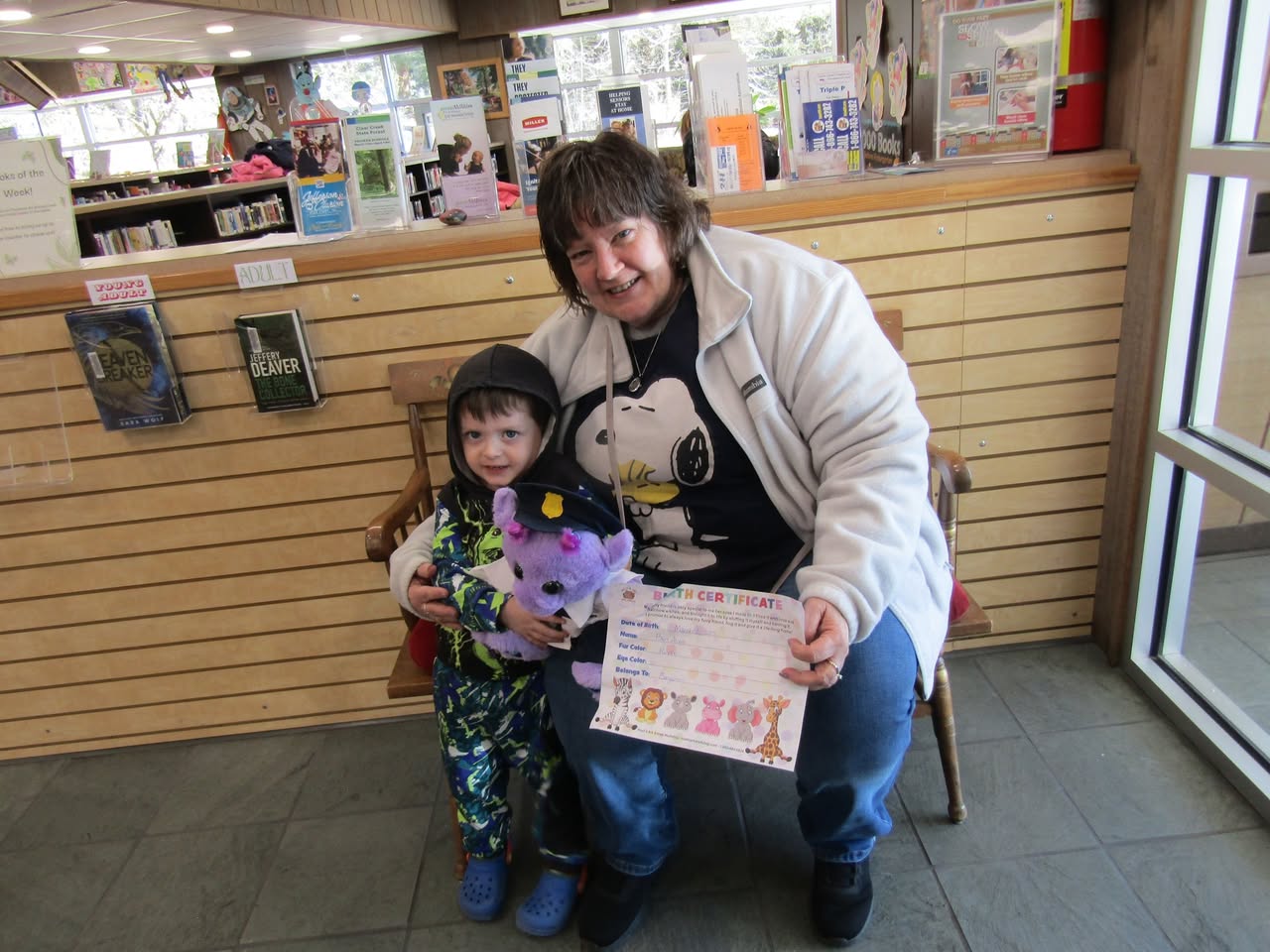 A child at a library workshop holding their handmade plush friend and artwork