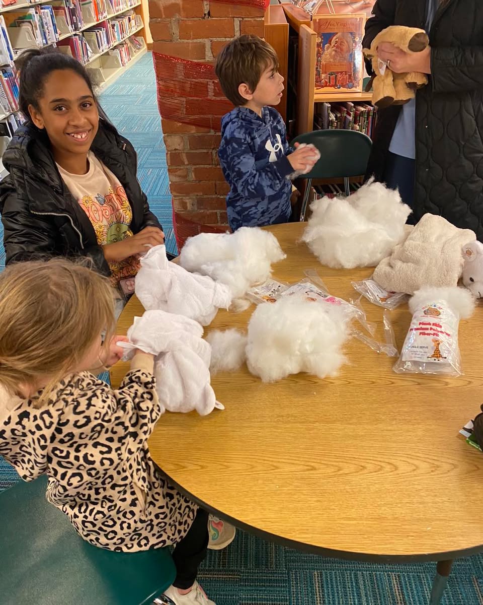 Four children holding their finished Furry Friends at a library workshop, with a librarian nearby