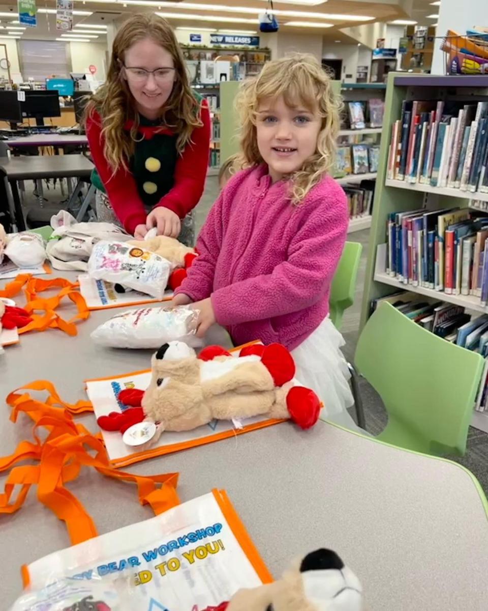 A child and workshop leader creating a stuffed animal together at a library event