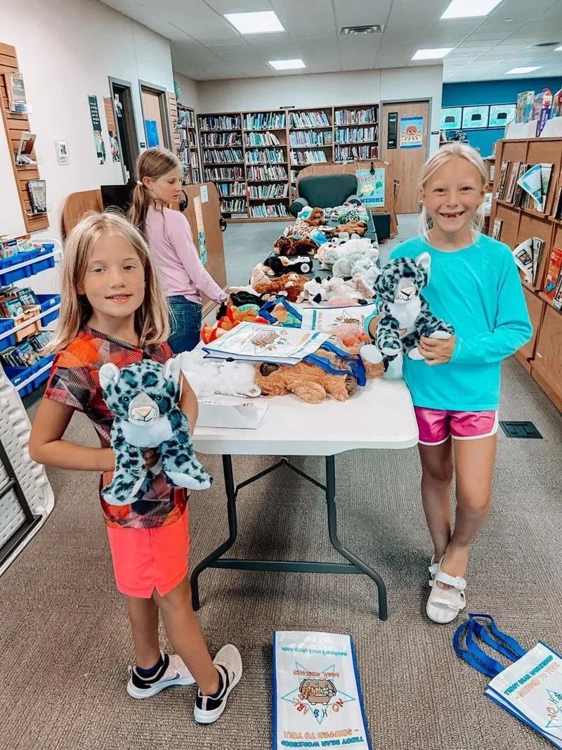 Children at a library workshop proudly holding the stuffed animals they created