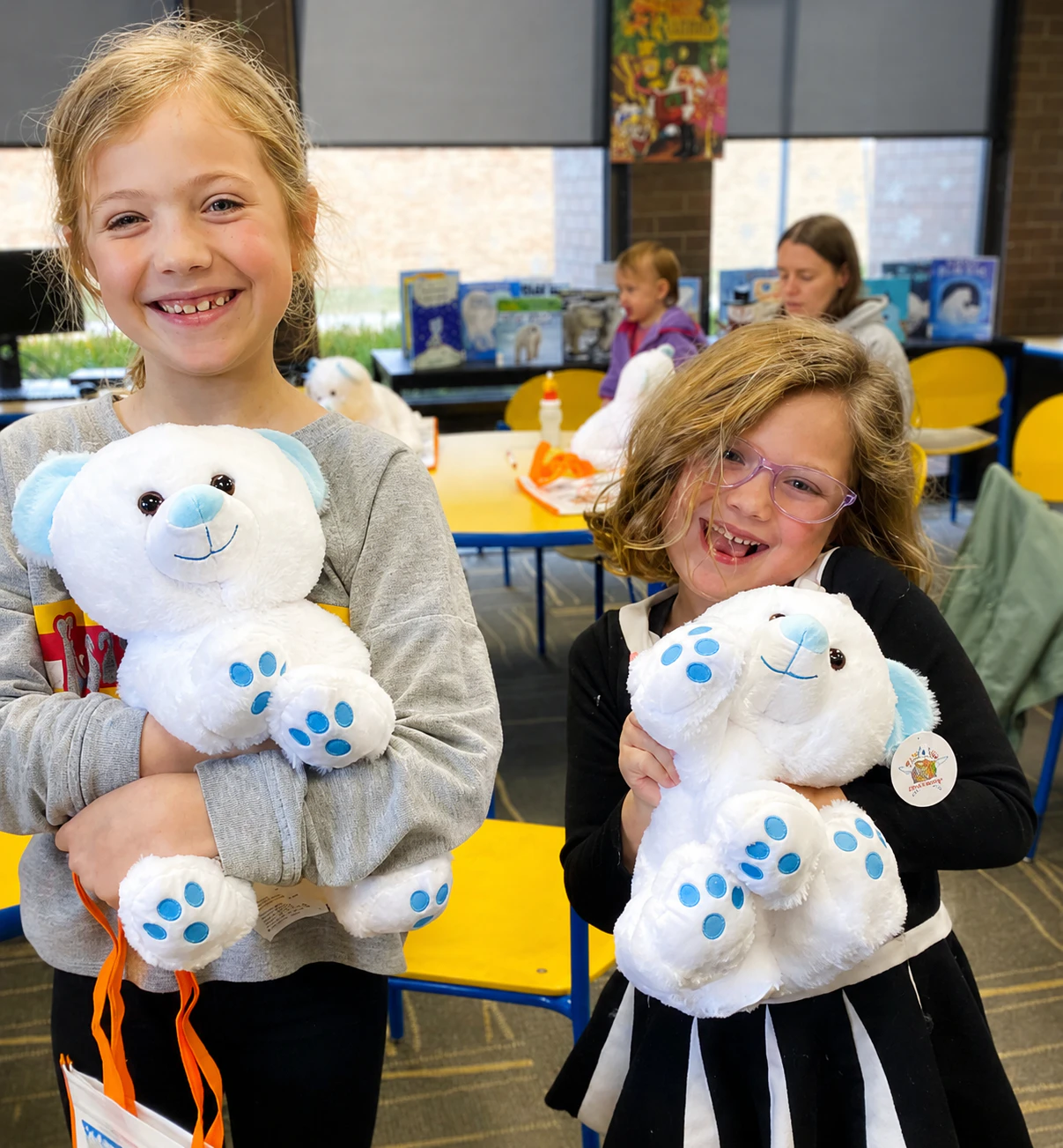 Two smiling kids each holding their finished polar bear Furry Friend at a Noah's Ark Animal Workshop event
