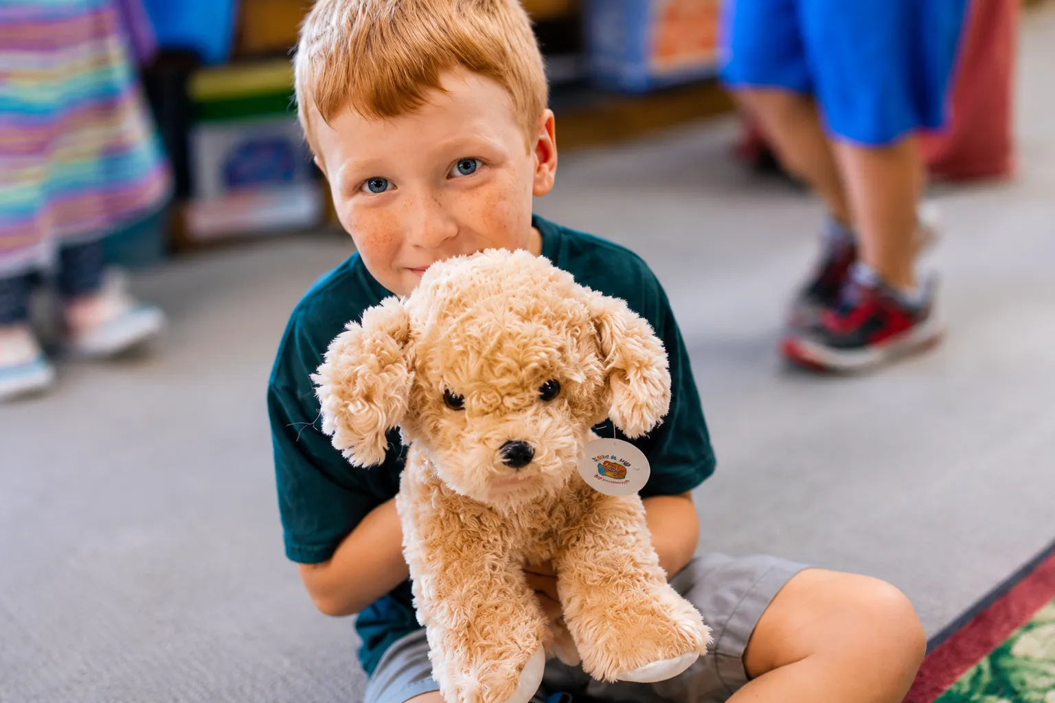 A young boy hugging the plush puppy he made at a Noah's Ark Animal Workshop group event