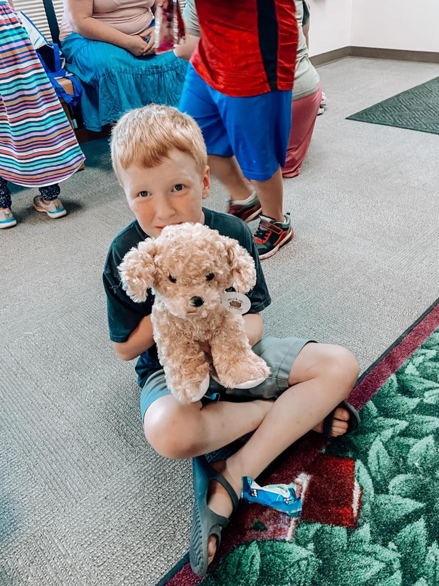 A young boy sitting cross-legged holding his finished plush dog